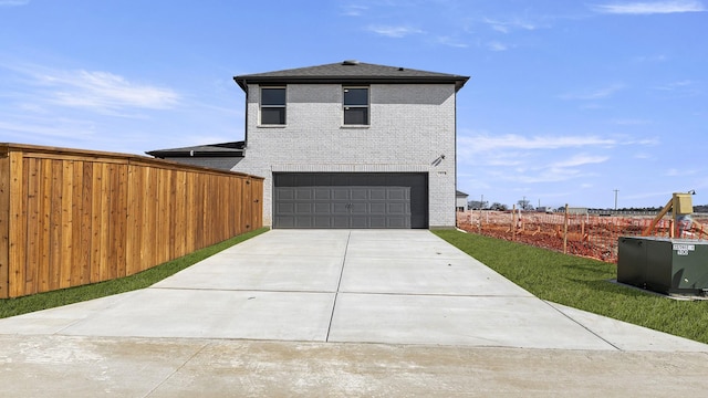 view of front of property featuring a garage, fence, concrete driveway, and brick siding