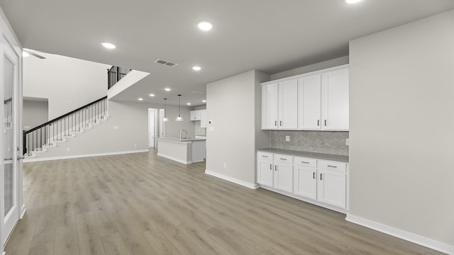 interior space featuring light wood-style flooring, recessed lighting, visible vents, baseboards, and stairway