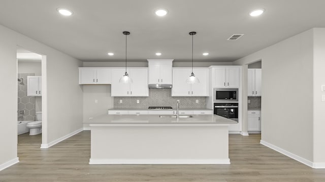 kitchen featuring an island with sink, appliances with stainless steel finishes, light countertops, and a sink