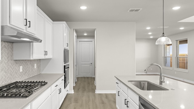 kitchen featuring decorative light fixtures, light countertops, visible vents, appliances with stainless steel finishes, and a sink