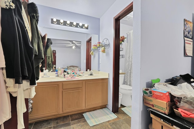 bathroom featuring toilet, vanity, and ceiling fan