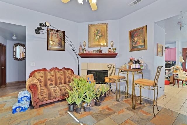 living room featuring ceiling fan and a tile fireplace