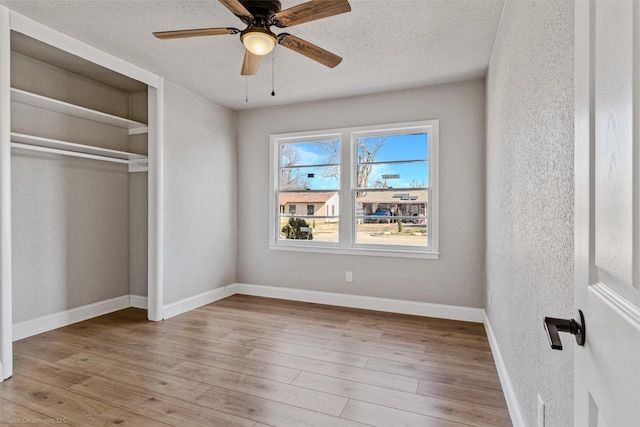 unfurnished bedroom featuring light wood-type flooring, a textured ceiling, a closet, and ceiling fan