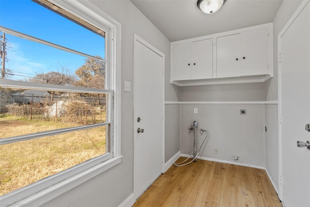 clothes washing area featuring hookup for an electric dryer, cabinets, and light hardwood / wood-style flooring