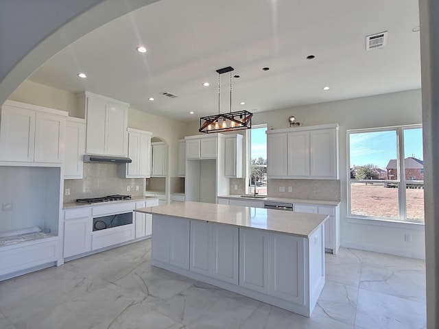 kitchen featuring white cabinetry, tasteful backsplash, hanging light fixtures, a kitchen island, and sink