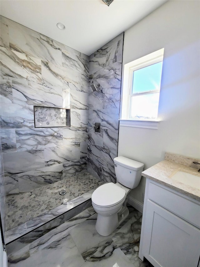 bathroom with vanity, toilet, and tiled shower