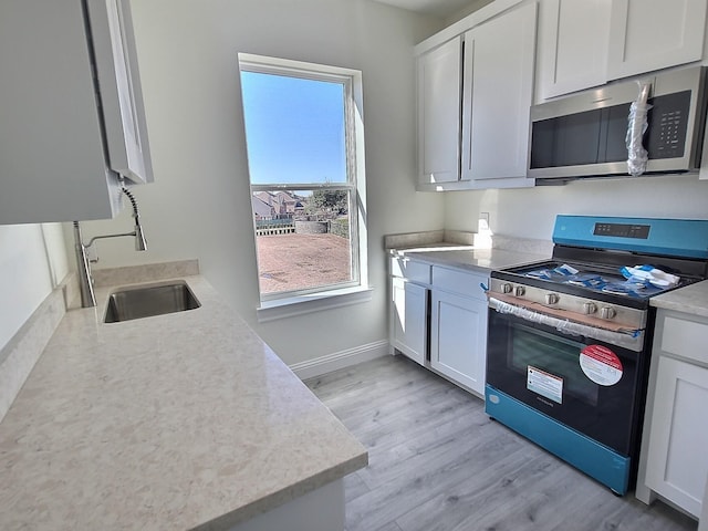 kitchen featuring white cabinets, appliances with stainless steel finishes, sink, and light hardwood / wood-style flooring