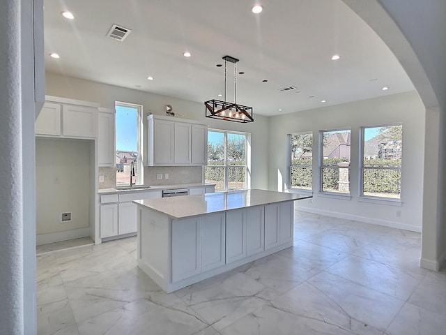 kitchen with tasteful backsplash, pendant lighting, a center island, sink, and white cabinetry