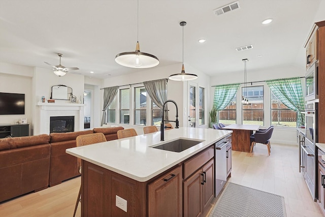 kitchen with a kitchen island with sink, sink, pendant lighting, and stainless steel appliances