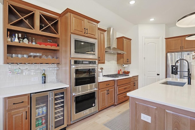 kitchen featuring wine cooler, wall chimney exhaust hood, sink, stainless steel appliances, and backsplash