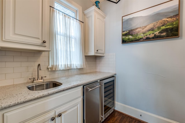 kitchen featuring white cabinetry, backsplash, beverage cooler, light stone countertops, and sink