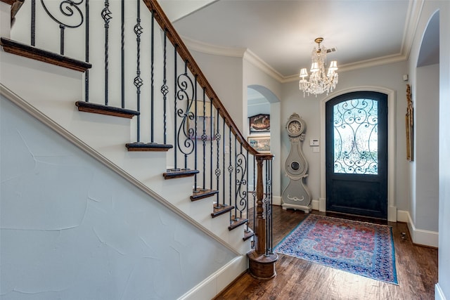 foyer entrance featuring dark hardwood / wood-style flooring, ornamental molding, and a chandelier