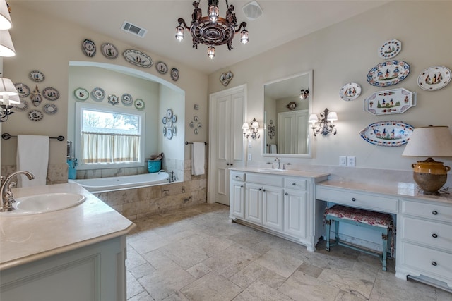 bathroom featuring tiled bath, vanity, and an inviting chandelier