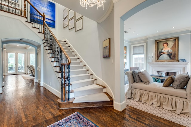 staircase featuring a chandelier, hardwood / wood-style floors, crown molding, and french doors