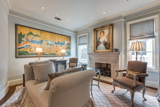 sitting room with a wealth of natural light, crown molding, and light hardwood / wood-style floors