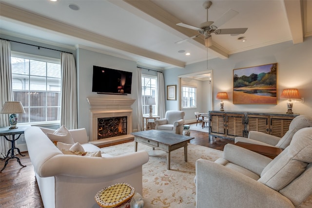 living room featuring hardwood / wood-style flooring, beam ceiling, ornamental molding, and ceiling fan