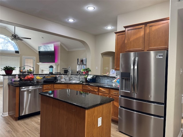 kitchen featuring appliances with stainless steel finishes, a kitchen island, dark stone counters, sink, and ceiling fan