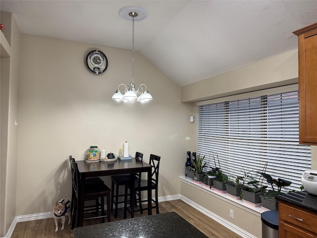 dining room with dark hardwood / wood-style flooring, a notable chandelier, and vaulted ceiling