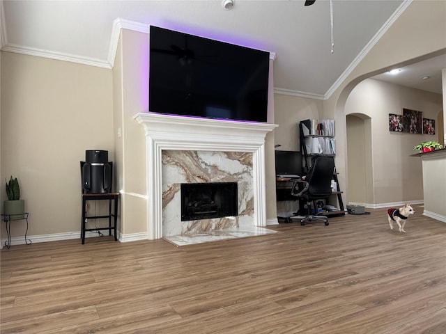 living room featuring vaulted ceiling, a high end fireplace, crown molding, and light wood-type flooring