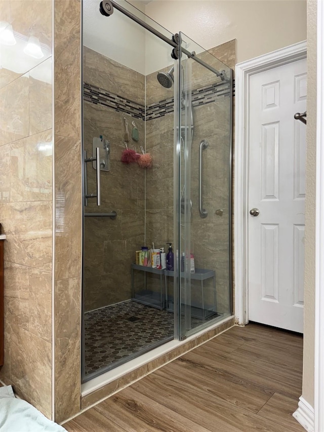 bathroom with a shower with shower door and wood-type flooring