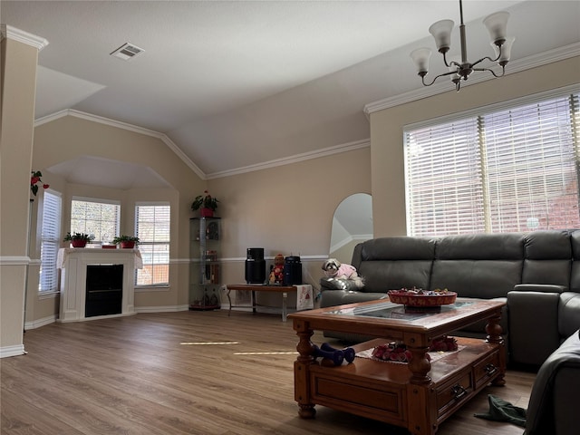 living room featuring crown molding, lofted ceiling, hardwood / wood-style floors, and a notable chandelier