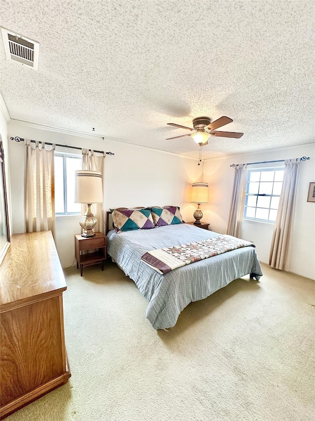 bedroom with a textured ceiling, ceiling fan, carpet floors, and multiple windows