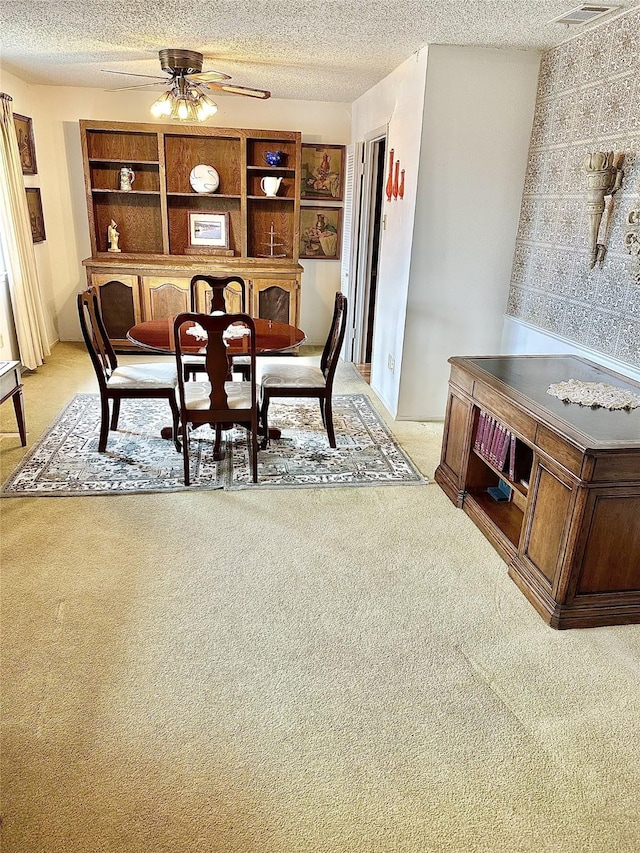 dining space with a textured ceiling, ceiling fan, and light colored carpet