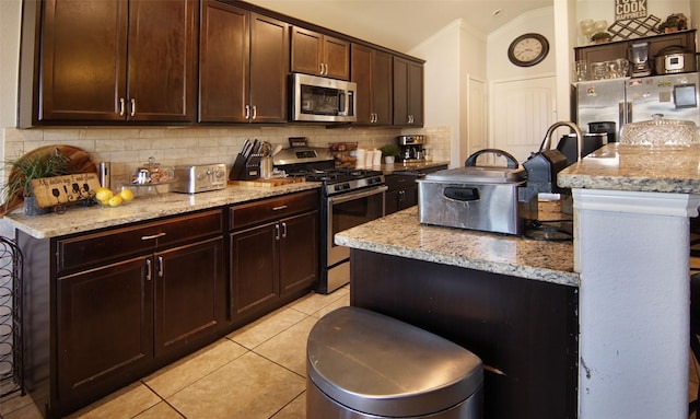 kitchen with light stone countertops, appliances with stainless steel finishes, tasteful backsplash, and vaulted ceiling