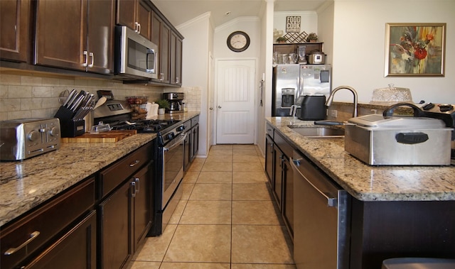 kitchen with sink, light stone countertops, appliances with stainless steel finishes, ornamental molding, and light tile patterned floors