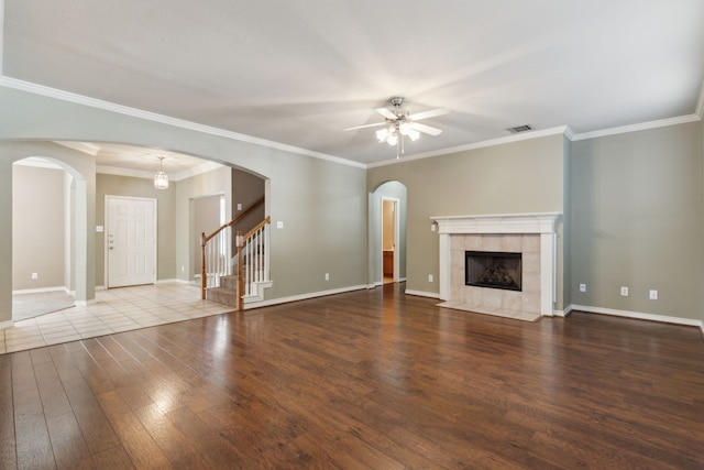 unfurnished living room featuring ceiling fan, a tiled fireplace, ornamental molding, and hardwood / wood-style floors