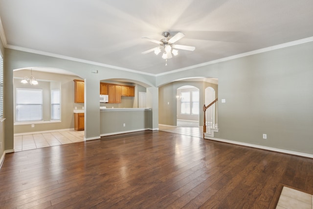 unfurnished living room with ceiling fan with notable chandelier, wood-type flooring, and ornamental molding