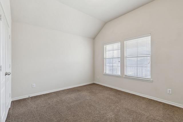 spare room featuring lofted ceiling and carpet