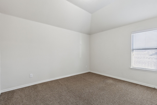 carpeted empty room featuring vaulted ceiling