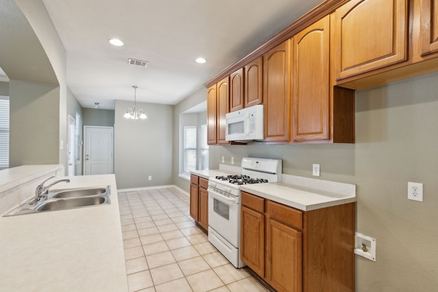 kitchen with light tile patterned floors, decorative light fixtures, white appliances, a chandelier, and sink