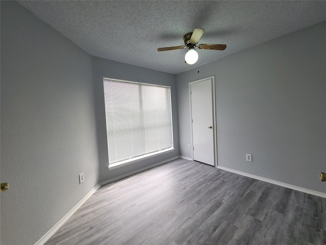 empty room featuring plenty of natural light, dark hardwood / wood-style floors, and a textured ceiling