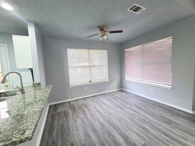 unfurnished dining area with ceiling fan, hardwood / wood-style floors, sink, and a textured ceiling