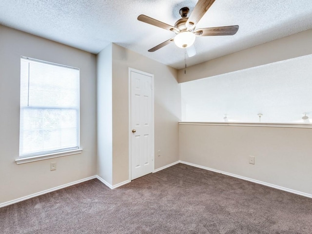 unfurnished room featuring ceiling fan, a healthy amount of sunlight, a textured ceiling, and carpet flooring