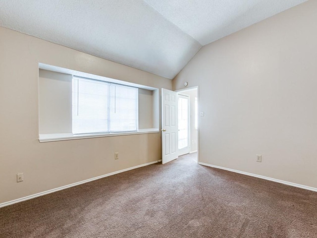 carpeted empty room featuring vaulted ceiling