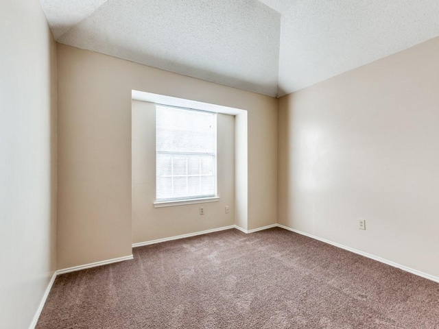 empty room with carpet floors, a textured ceiling, and vaulted ceiling