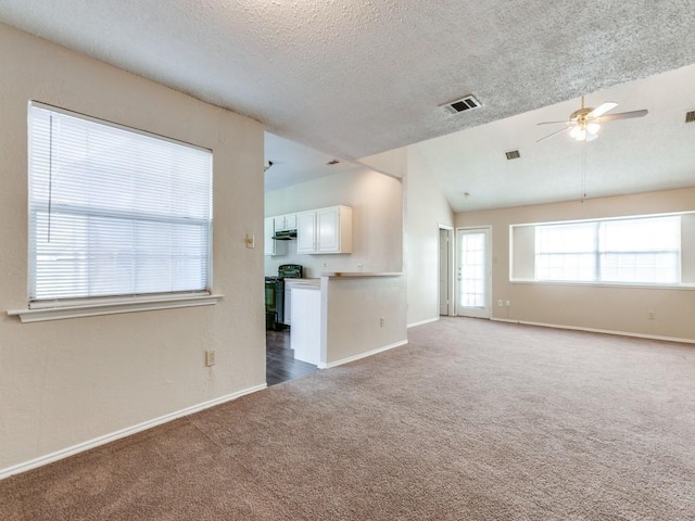 unfurnished living room featuring carpet floors, vaulted ceiling, a textured ceiling, and ceiling fan