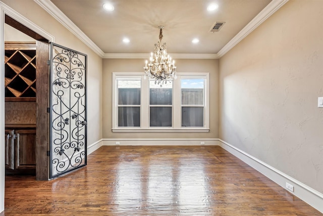 unfurnished dining area with dark hardwood / wood-style floors, ornamental molding, and a notable chandelier