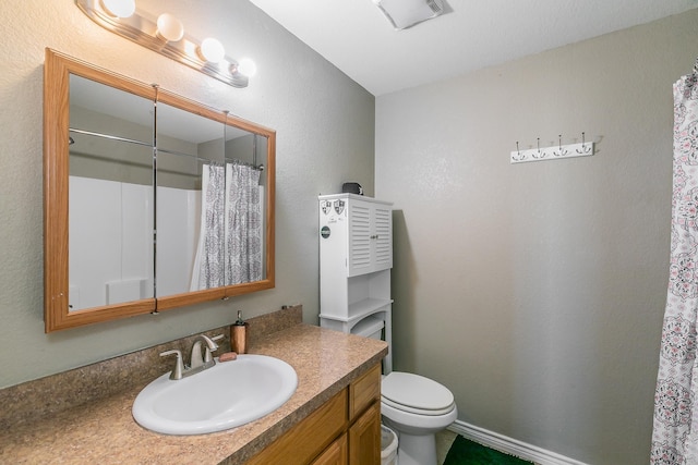 bathroom featuring toilet, walk in shower, and vanity