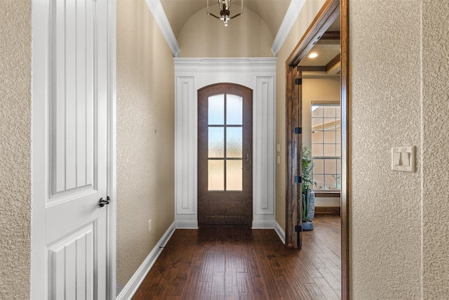 entrance foyer with vaulted ceiling, dark wood-type flooring, and ornamental molding