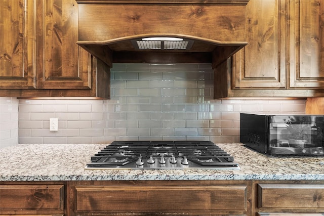 kitchen featuring stainless steel gas cooktop, tasteful backsplash, and light stone countertops