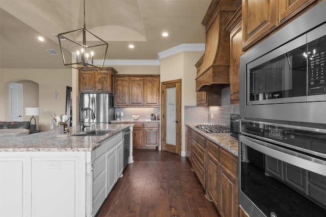 kitchen with tasteful backsplash, a large island with sink, sink, appliances with stainless steel finishes, and custom range hood