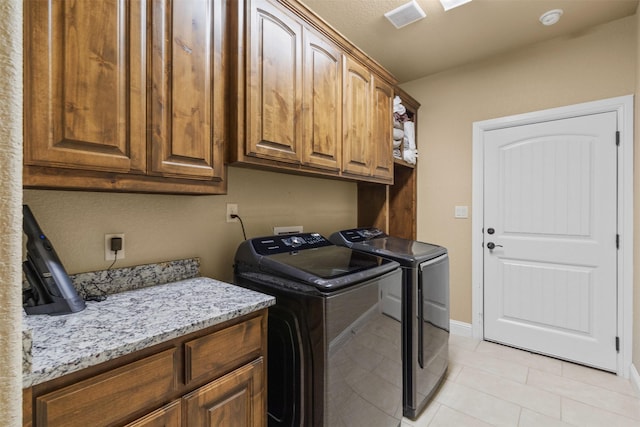 laundry room featuring washer and clothes dryer, light tile patterned floors, and cabinets