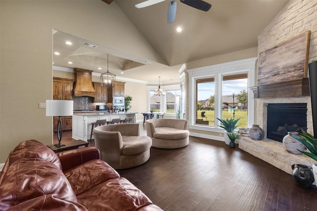 living room with ceiling fan with notable chandelier, dark hardwood / wood-style floors, high vaulted ceiling, and a fireplace