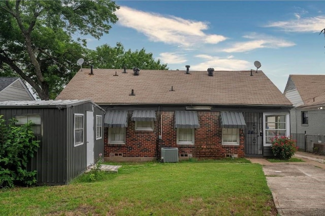 rear view of house featuring central air condition unit and a yard