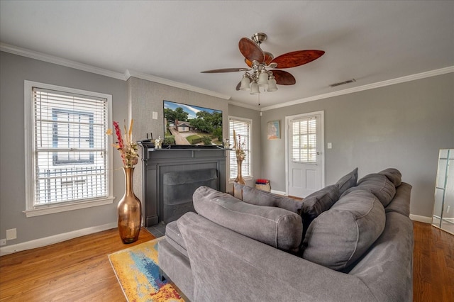 living room with ceiling fan, light hardwood / wood-style flooring, ornamental molding, and a healthy amount of sunlight