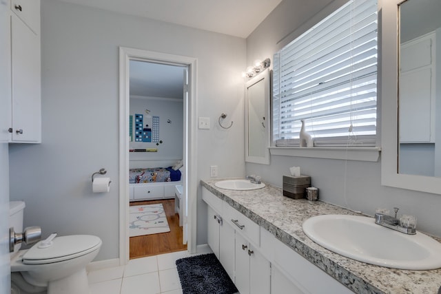 bathroom with toilet, vanity, and tile patterned flooring